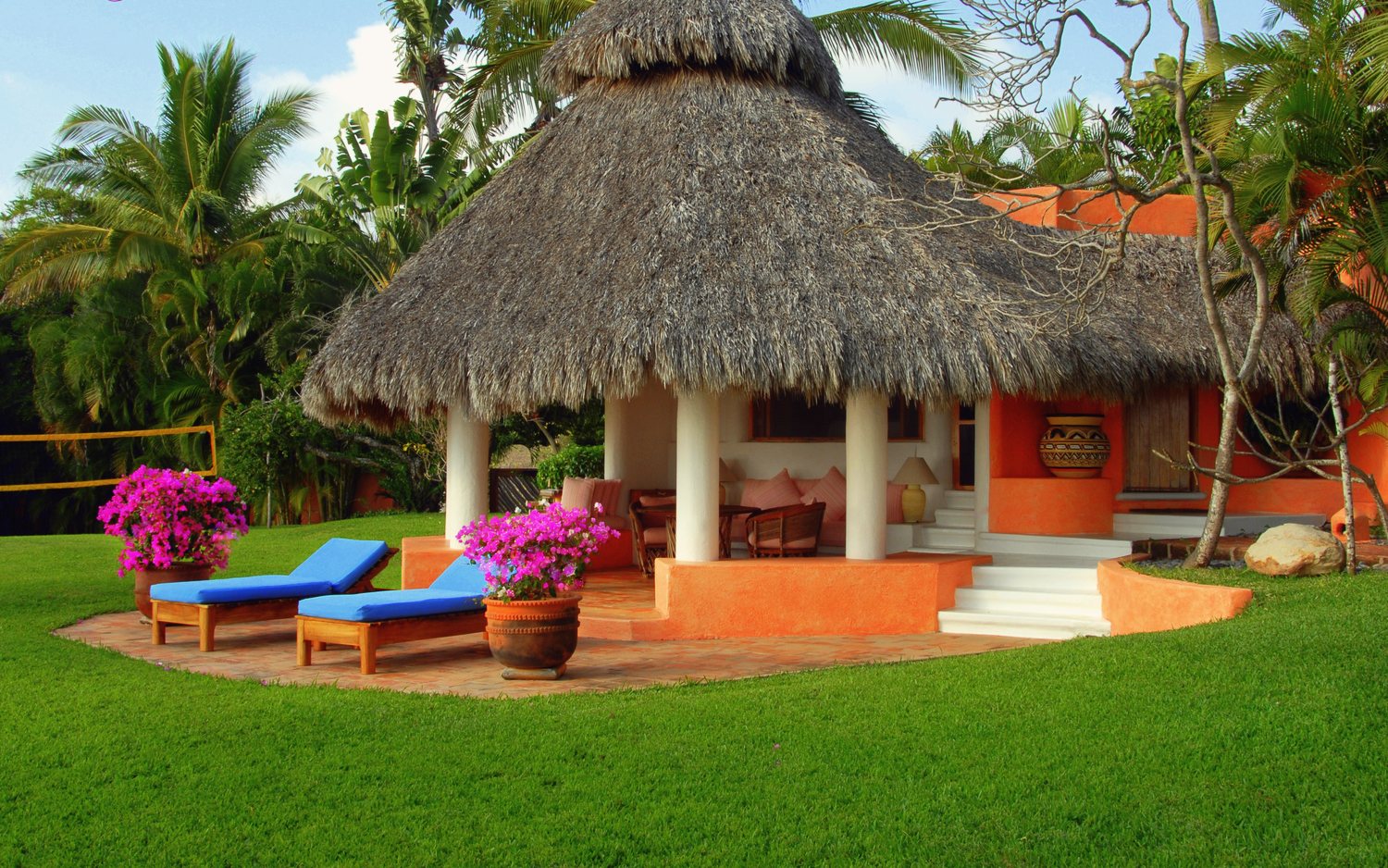The Guest Casita exterior: a thatched palapa living area with sun loungers and bougainvillea on the lawn