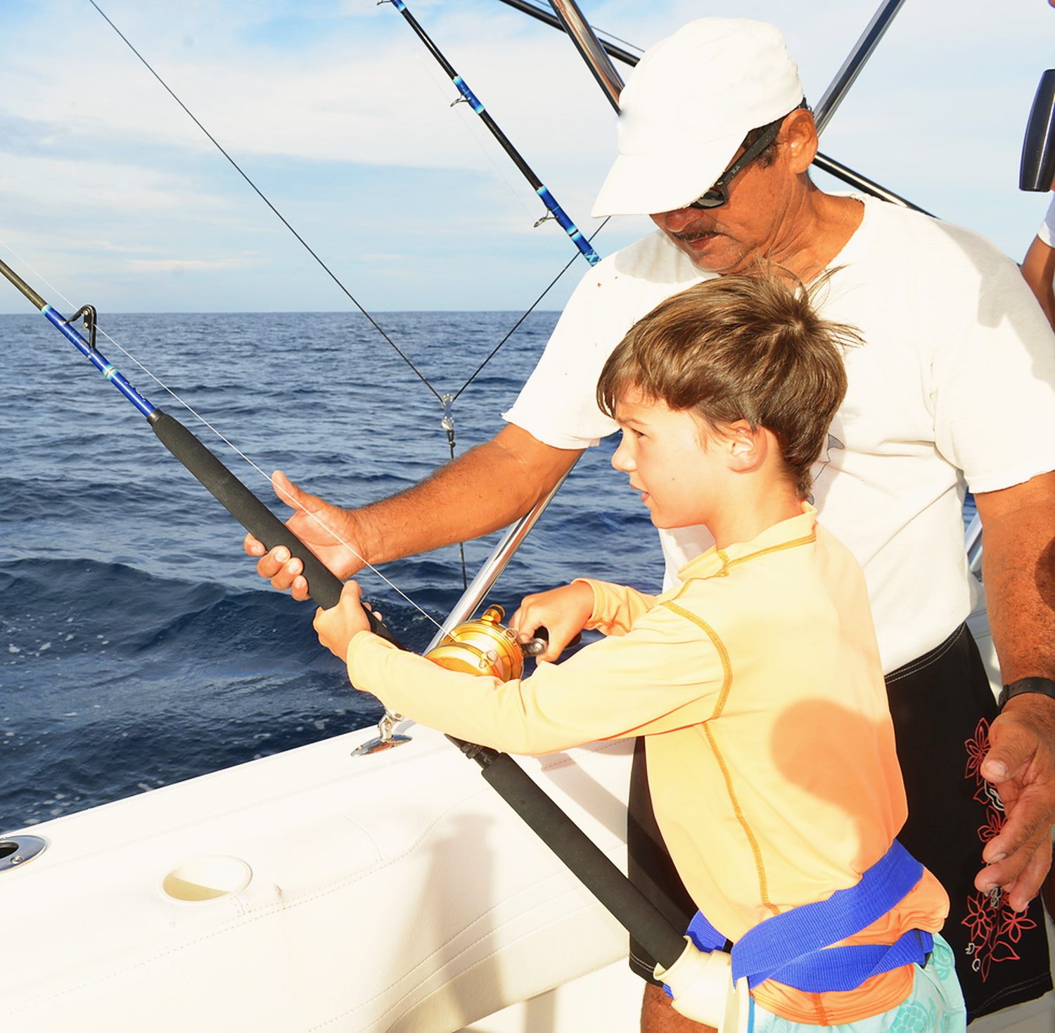 A boy and a captain reeling in a line on a fishing boat