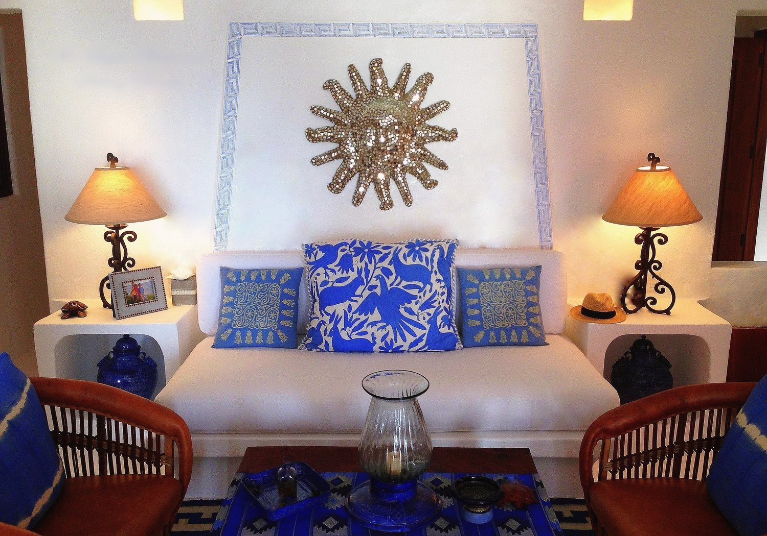 The Lapis sitting room: white sofa with blue embroidered cushions beneath a silver sun mirror