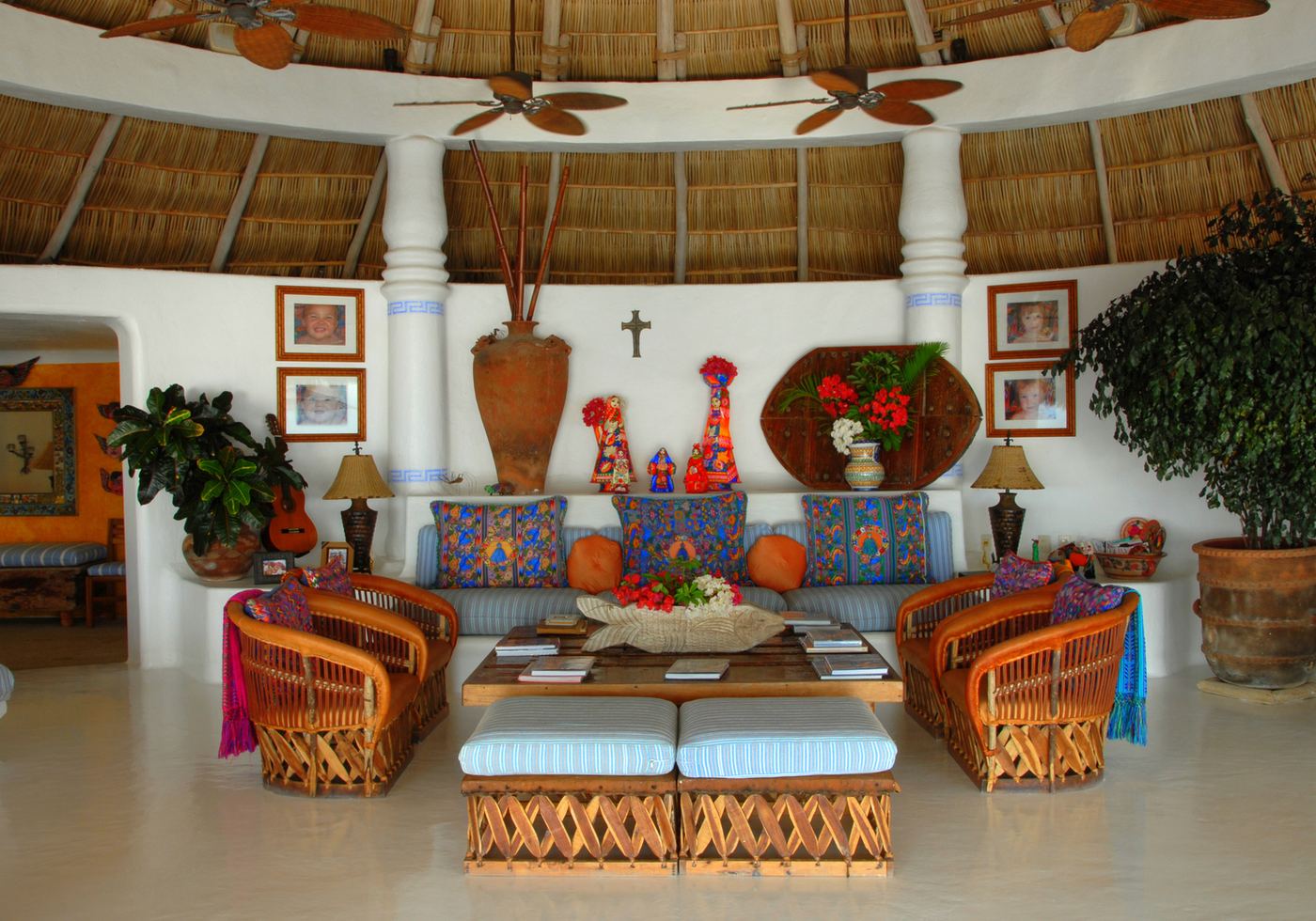 The living palapa: thatched ceiling, white columns, folk-art cushions and equipale chairs