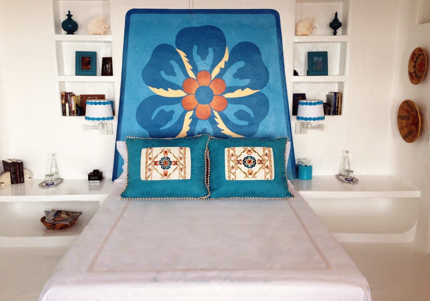 The Pariba bedroom: Cal-King bed with a painted blue flower headboard, teal cushions and white built-in shelves