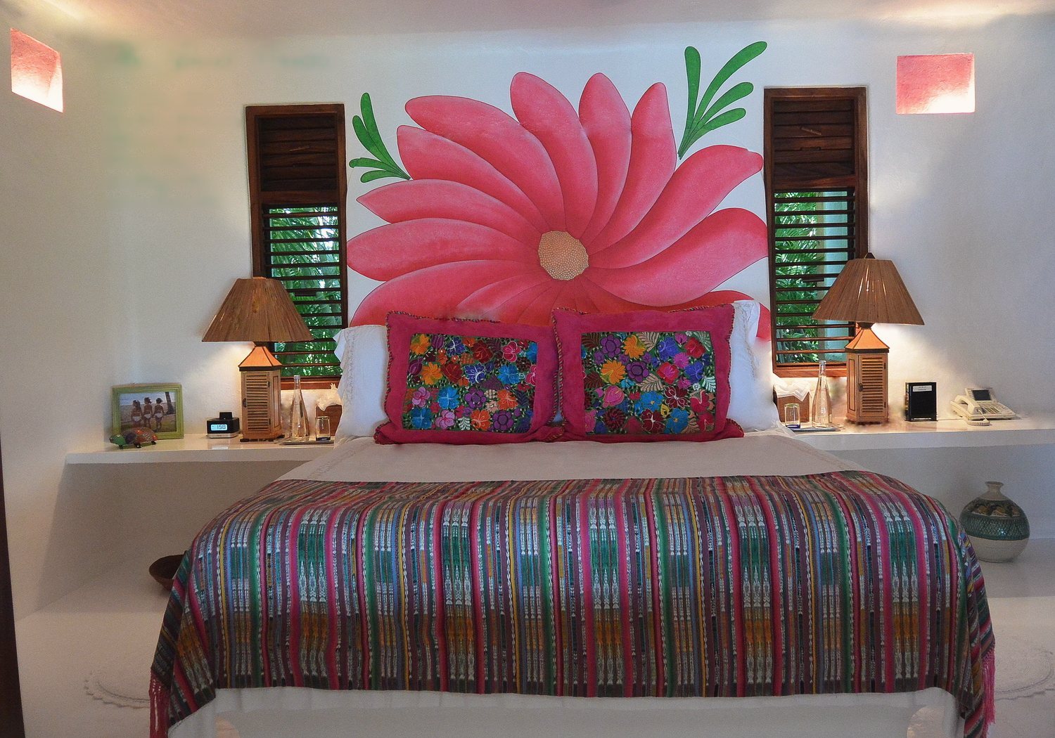 The Guest Casita bedroom: Cal-King bed beneath a large painted pink flower mural, with woven textiles