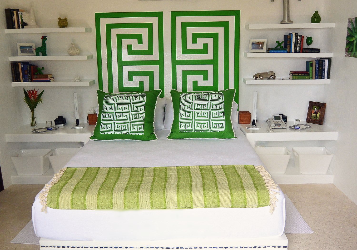 The Emerald bedroom: Cal-King bed with a green Greek-key headboard, green cushions and a striped throw
