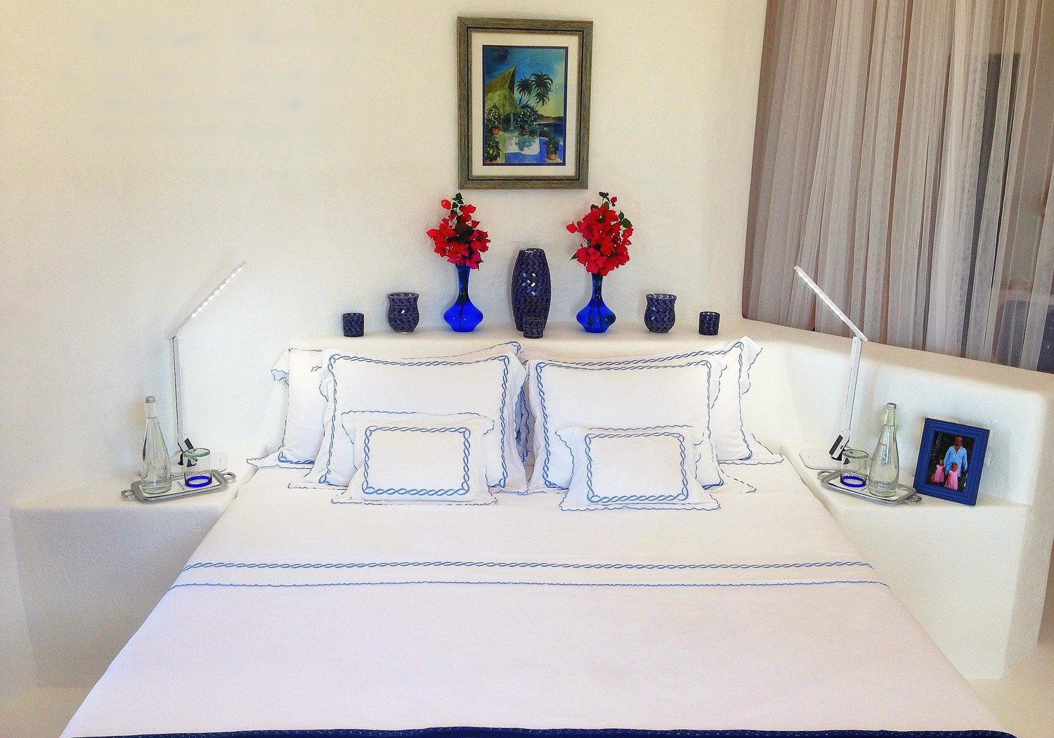 The Lapis bedroom: Cal-King bed in white and blue linens with blue vases on the headboard ledge