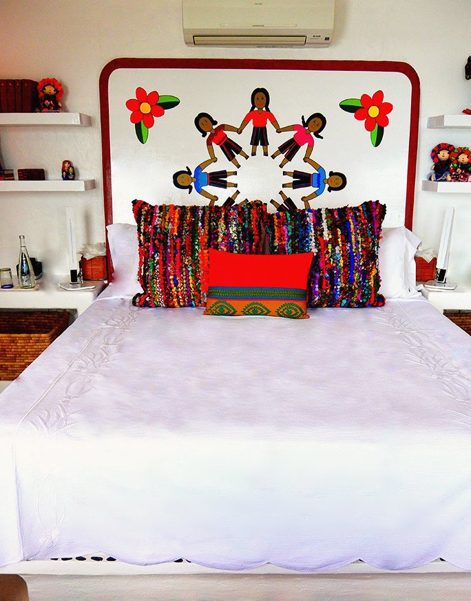The Ruby bedroom: Cal-King bed with a hand-painted headboard of children in a ring and bright woven pillows