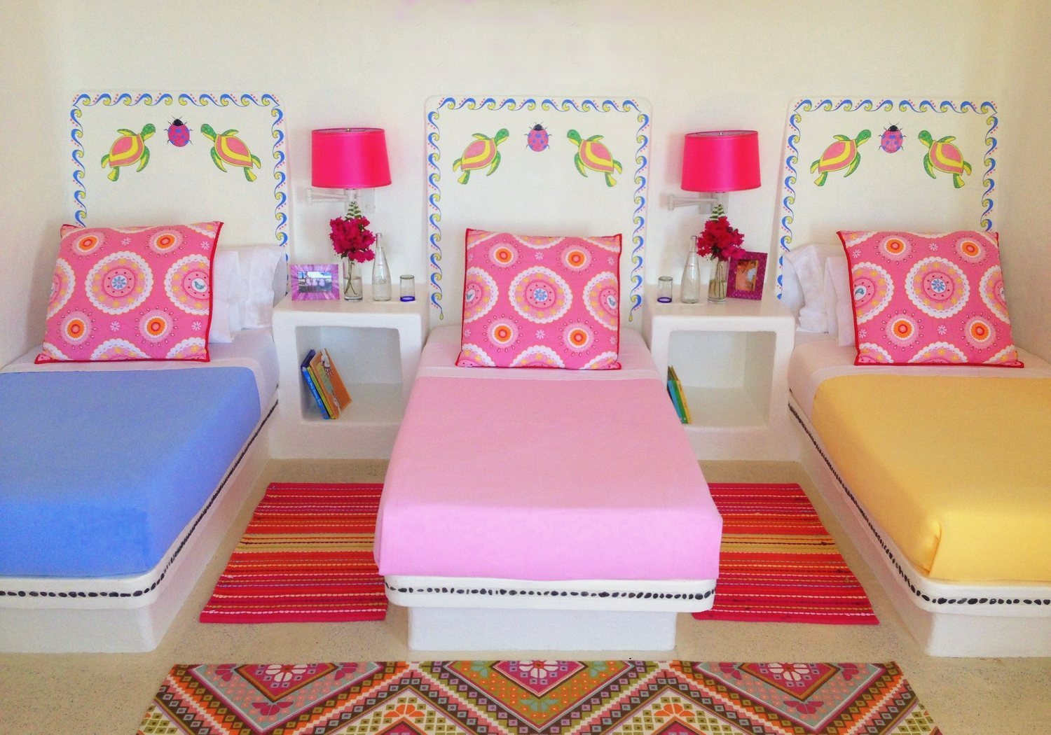 The Tourmaline bedroom: three twin beds with painted turtle headboards and pink cushions